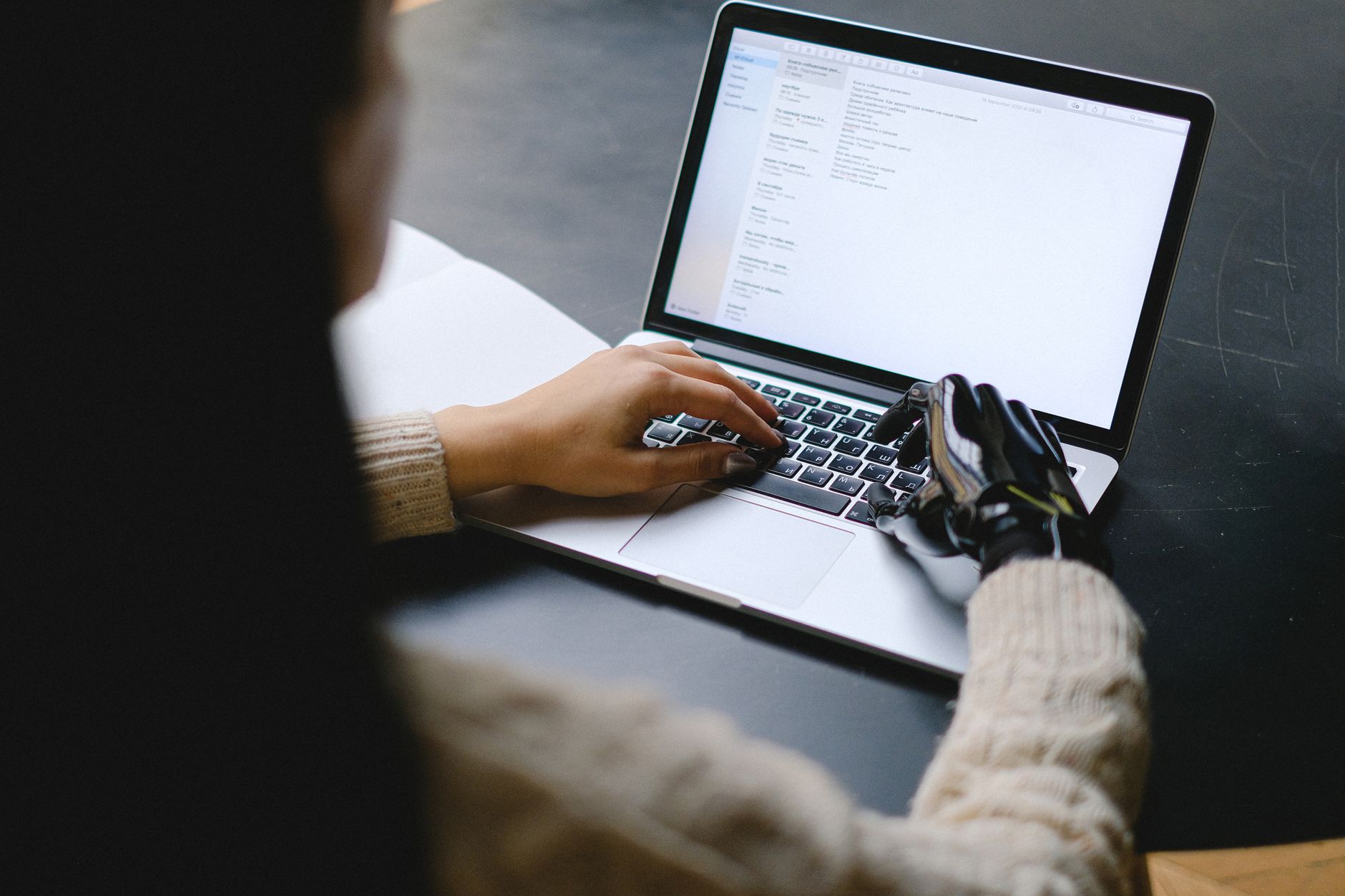 A person typing an AI writing prompt on a laptop with a phone nearby