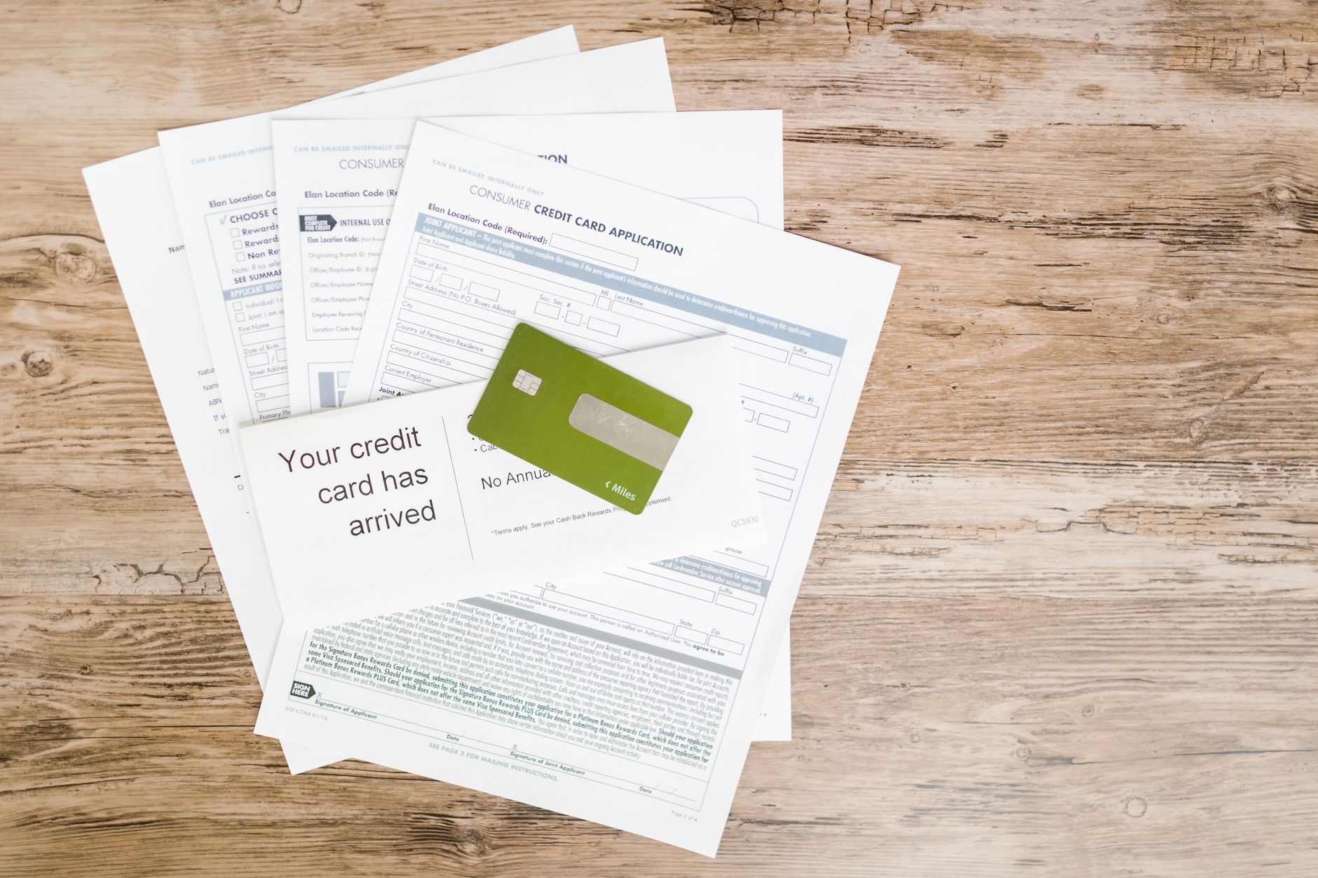 A stack of notebooks and a credit card on a desk showing subscription planning.