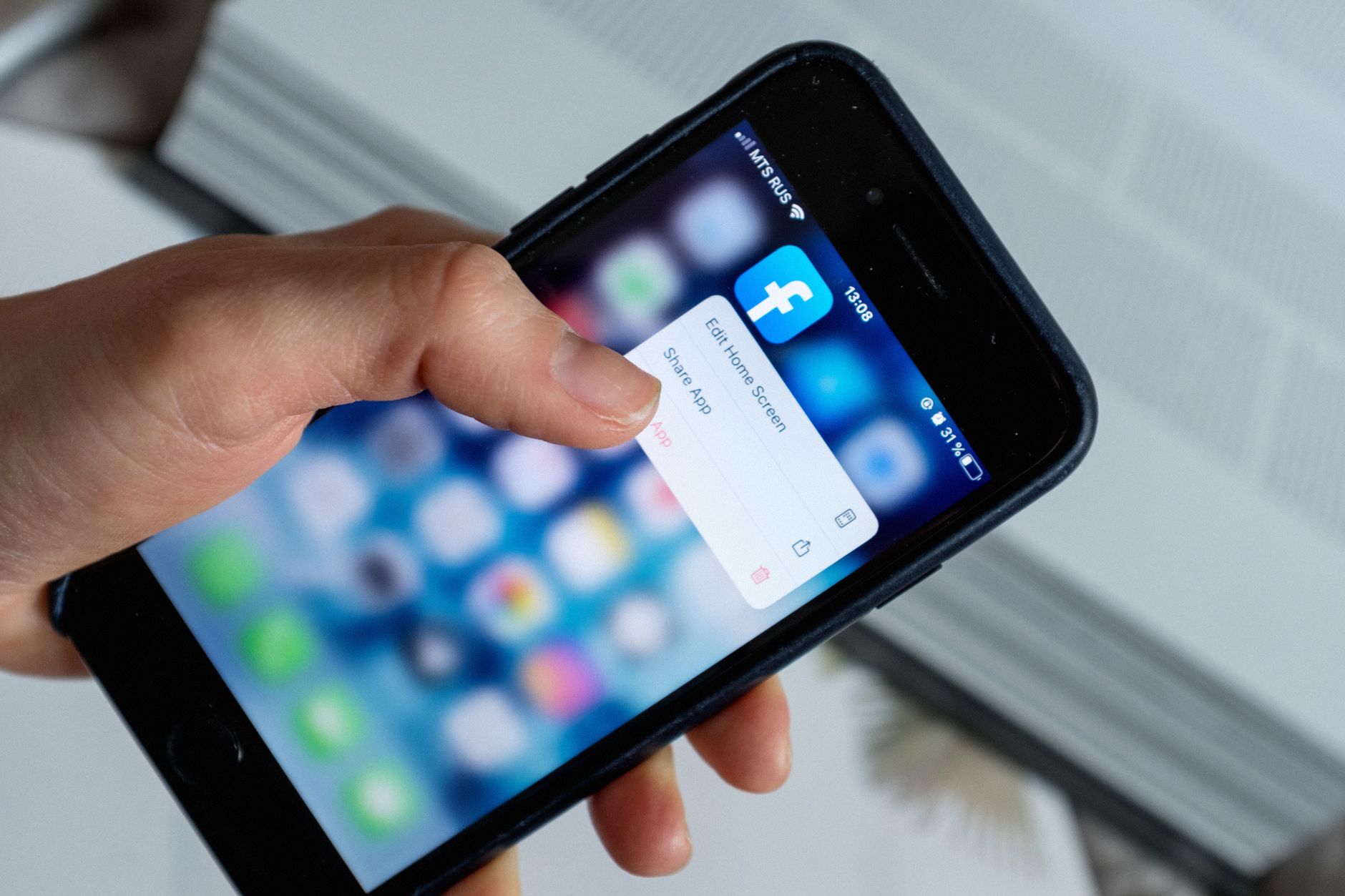 A person deleting unused marketing app icons from a smartphone screen.
